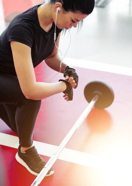 woman preparing for her weightlifting workout with small barbell - 写真・画像