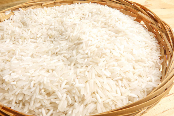 Fresh rice in wicker basket over a wooden table. Side lighting effect. - Photo, Image
