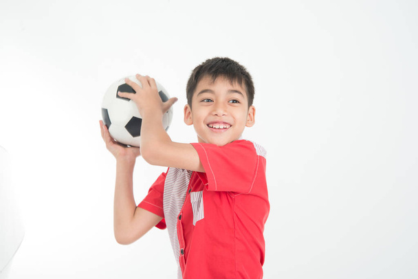 Πορτρέτο του μικρού αγοριού λαμβάνουν ένα πόδι μπάλα με το χέρι σε λευκό φόντο - Φωτογραφία, εικόνα