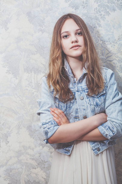 young beautiful girl with blond hair standing on the background of wall with wallpape - Foto, imagen