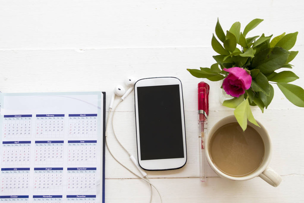 kannettavan kalenterin suunnittelija matkapuhelin liiketoiminnan työtä kuuma kahvi pöydällä valkoinen toimistopöytä
 - Valokuva, kuva