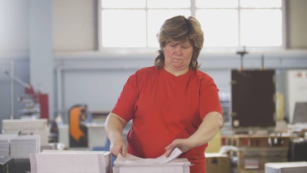 Trabalhadoras do sexo feminino que classificam uma pilha de papel na tipografia
 - Foto, Imagem
