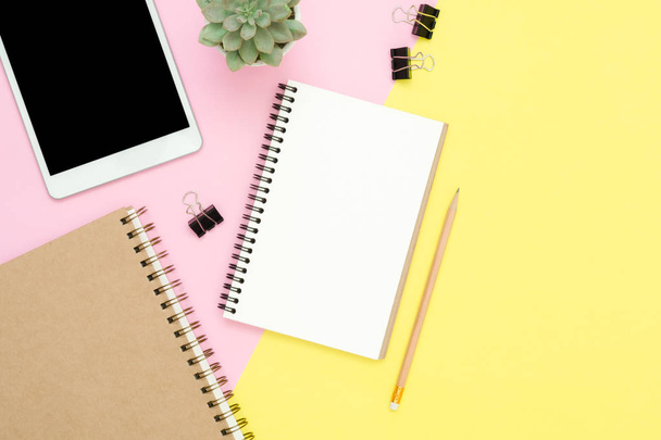 Γραφείο εργασίας χώρου - επίπεδη θέσει φωτογραφία κάτοψη του χώρου εργασίας με κενό mock up δένδρο εγκαταστάσεων tablet και notebook σε παστέλ φόντο. Έννοια επιφάνεια του παστέλ ροζ χρώμα κίτρινο αντίγραφο χώρου εργασίας. - Φωτογραφία, εικόνα
