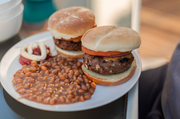 Abendessen mit klassischen Burgern und gebackenen Bohnen im Sommer auf der hinteren Terrasse. - Foto, Bild