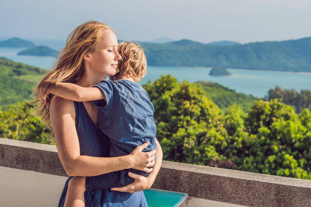 Mother and son on background with tropical beach landscape panorama. Beautiful turquoise ocean waves with boats and sandy coastline from high view point. Phuket, Thailand. Traveling with children concept. - Photo, image