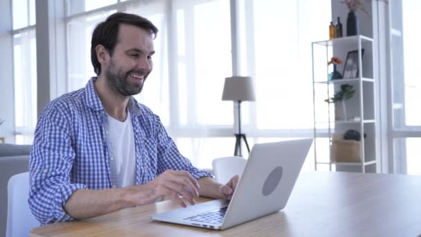Chat de vídeo en línea en el ordenador portátil en el trabajo por el hombre de la barba casual
 - Imágenes, Vídeo