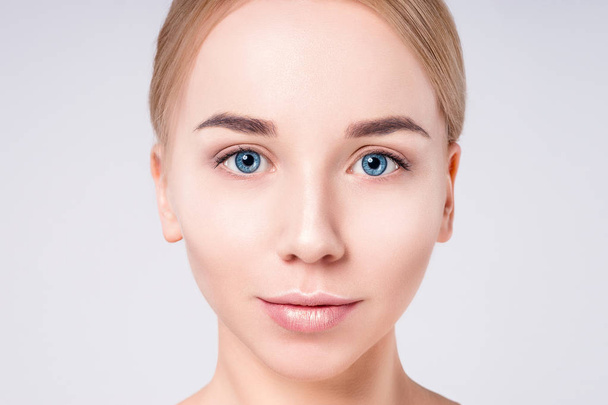 Woman beautiful face portrait. Beauty Portrait. Beautiful Spa model Girl with Perfect Fresh Clean Skin. Blonde female looking at camera at gray background. Youth and Skin Care Concept. - Fotografie, Obrázek