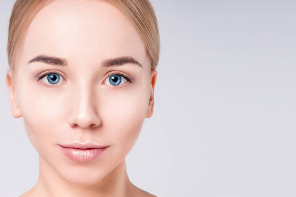 Woman beautiful face portrait. Beauty Portrait. Beautiful Spa model Girl with Perfect Fresh Clean Skin. Blonde female looking at camera at gray background. Youth and Skin Care Concept. - Photo, Image