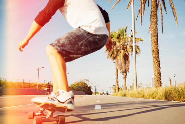 A man is skateboarding in a urban area with his back to the camera. Motion photo of a young guy on a longboard in a skatepark  - Фото, изображение