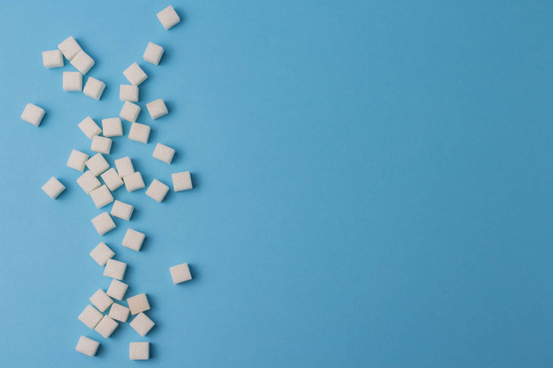 A lot of sugar cubes on a blue background. - Foto, afbeelding
