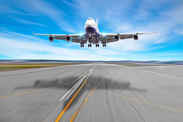 Passagier vliegtuig vier motor met een cast schaduw op het asfalt landing op een landingsbaan luchthaven. - Foto, afbeelding