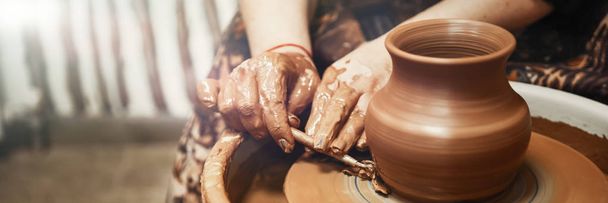 Ceramics. The master on the potter's wheel produces a vessel of clay, undercutting the form. - Photo, Image