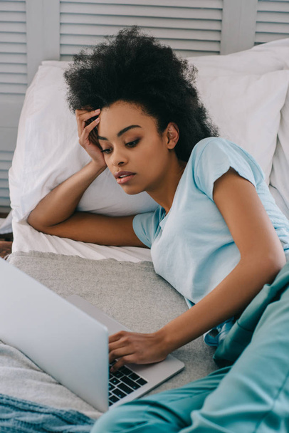 African american woman using laptop in bed - Photo, Image