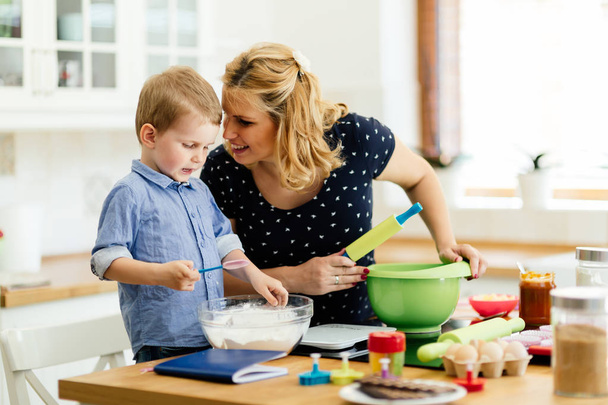 Child helping mother prepare muffins in kitchen - Zdjęcie, obraz