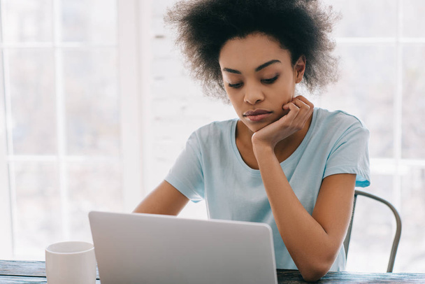 Przemyślane african american kobieta działa na laptopie w domu - Zdjęcie, obraz