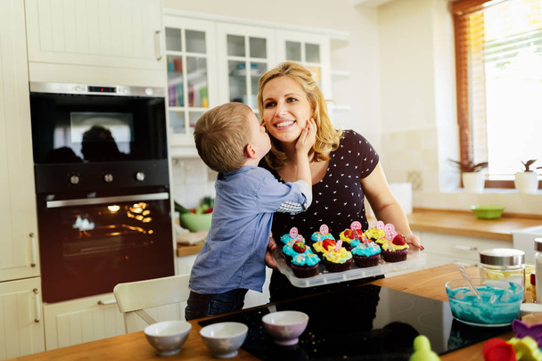 Child helping mother prepare muffins in kitchen - Foto, Imagen