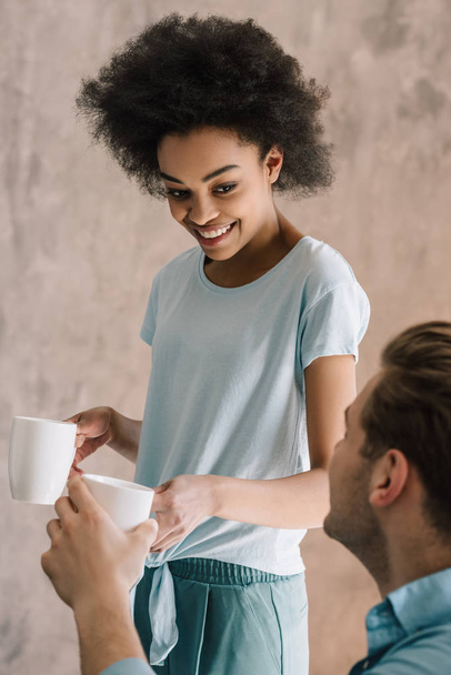 African american girl giving cup of coffee to her boyfriend - Photo, Image