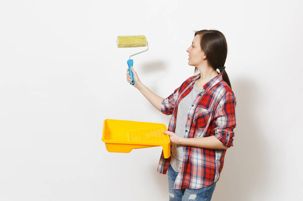 Молода красива жінка тримає лоток для фарби і вказує на фарбування стін на копіювальному просторі, ізольованому на білому тлі. Інструменти, інструменти для ремонту житлової кімнати. Ремонт домашньої концепції
. - Фото, зображення