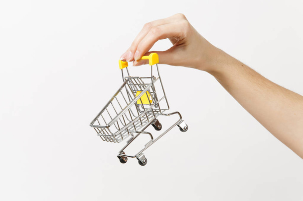 Close up of female hand horizontal holds toy metal shopping cart with yellow plastic handle isolated on white background. Shopping concept. Copy space for advertisement. - Φωτογραφία, εικόνα