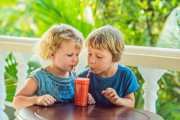 Children boy and girl drink orange smoothie from papaya - Zdjęcie, obraz