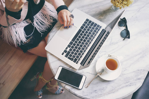 Jeune femme travaillant dans un café pendant la pause déjeuner. Lunettes de soleil, ordinateur portable et smartphone sur une table en marbre
. - Photo, image