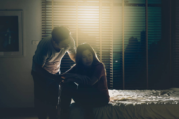 Couple déprimé assis tête dans les mains sur le lit dans la chambre sombre avec un environnement de faible luminosité, concept dramatique
 - Photo, image