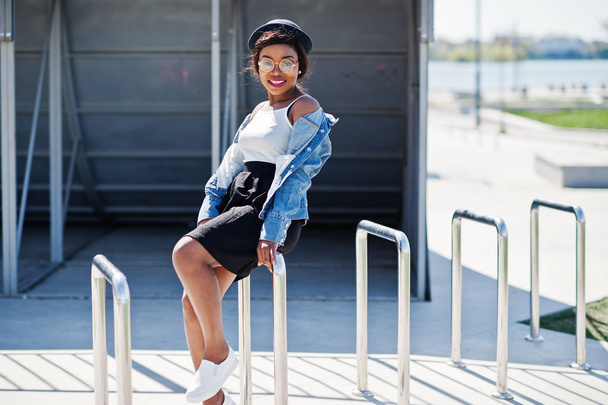 Stylish african american model in glasses hat, jeans jacket and  - Valokuva, kuva