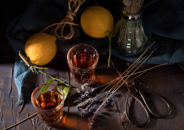 Rustikales Stillleben mit Tee oder Likör, Zitrusfrüchten und Lavendel - Foto, Bild