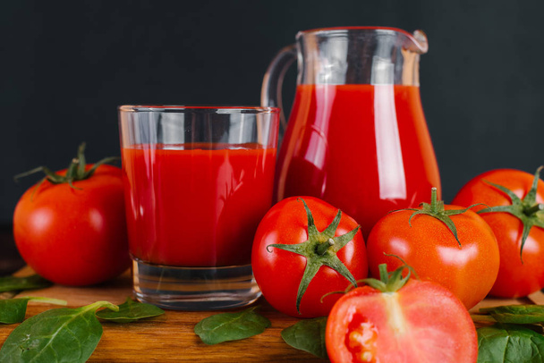 Jugo de tomate fresco y tomates en una mesa de madera
 - Foto, imagen