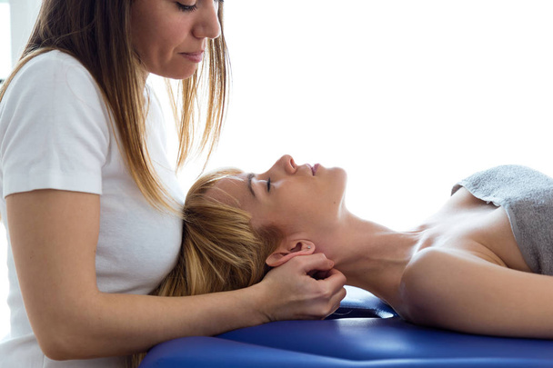 Young physiotherapist doing a neck treatment to the patient in a physiotherapy room. Rehabilitation, medical massage and manual therapy concept. - Photo, Image
