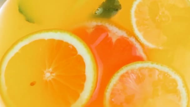 Uitzicht vanaf de bovenkant van de limonadepot met drijvende sinaasappels, grapefruits en verse muntblaadjes - Video