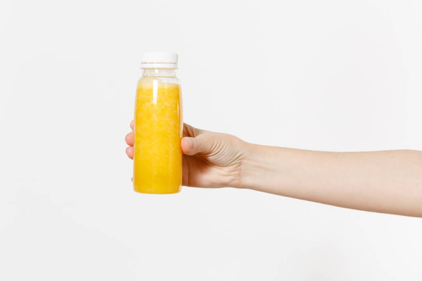 Close up female holding in hand yellow detox smoothies in bottle isolated on white background. Proper nutrition, vegetarian drink, healthy lifestyle, dieting concept. Advertising area for copy space. - Photo, Image