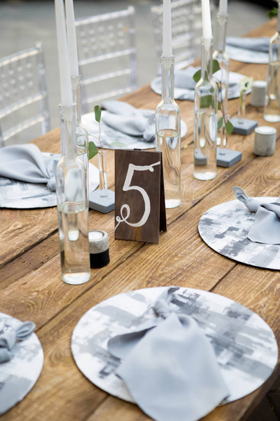 Tisch mit Essen und Blumen auf der Hochzeit. Nummer 5 auf weißer Karte steht vor dem Strauß in der Mitte des Esstisches - Foto, Bild