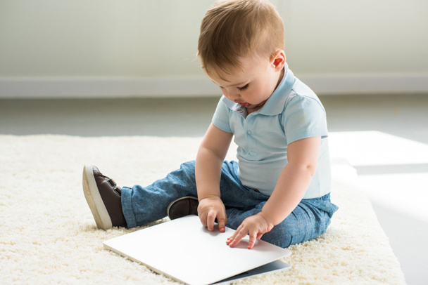 bambino piccolo con computer portatile seduto sul pavimento a casa
 - Foto, immagini