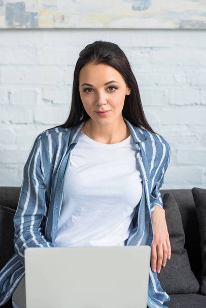 portrait of young woman with laptop resting on sofa at home - Foto, Bild