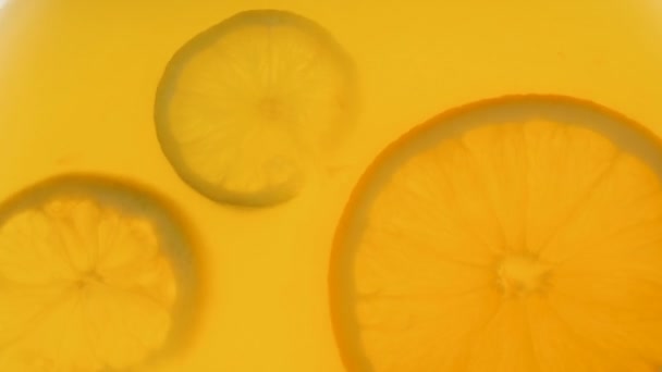 Fechar vídeo em câmera lenta de frutas cítricas fatias flutuando em suco de laranja
 - Filmagem, Vídeo