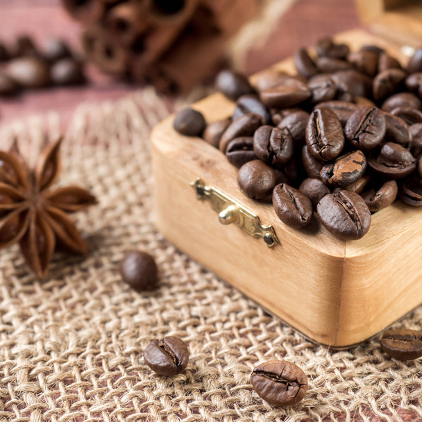 Coffee beans in a wooden box with cinnamon sticks and star anise on burlap napkins - Photo, Image