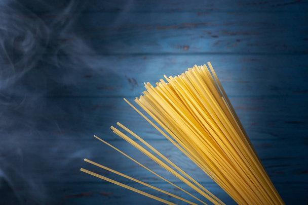 Un montón de espaguetis italianos sobre un fondo azul con humo
 - Foto, Imagen