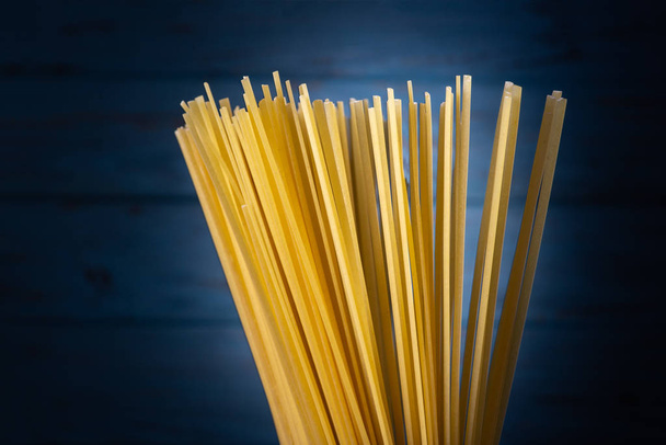 Dry Italian spaghetti on the kitchen  on a blue background - Foto, afbeelding