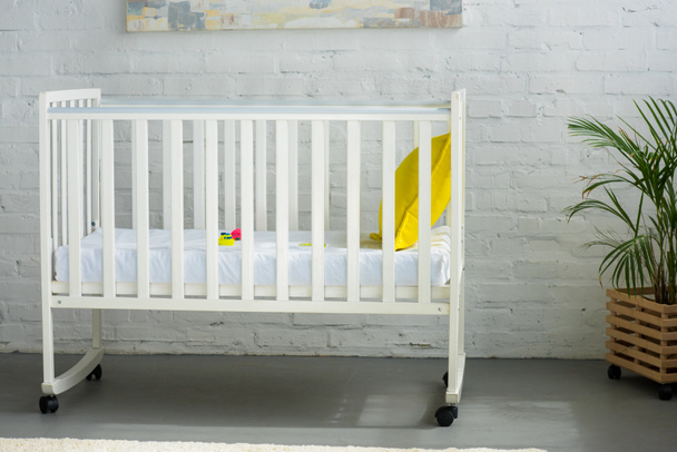 close up view of empty baby crib with yellow pillow in room - Fotoğraf, Görsel
