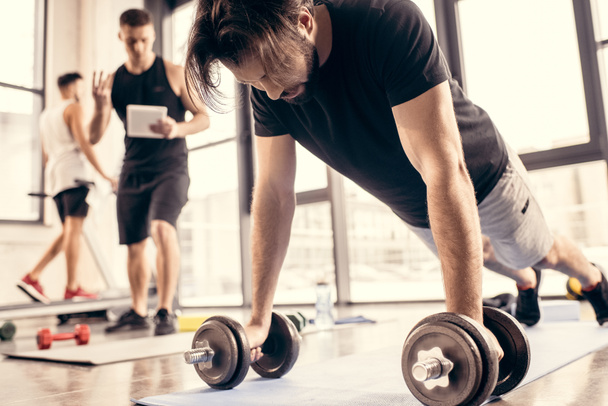 tired sportsman doing push ups on dumbbells in gym, trainer counting results - 写真・画像