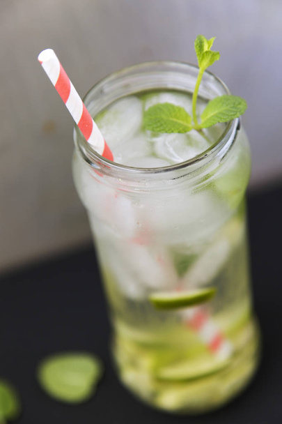 Summer drink with ice, lime and mint on dark background. Closeup - Zdjęcie, obraz