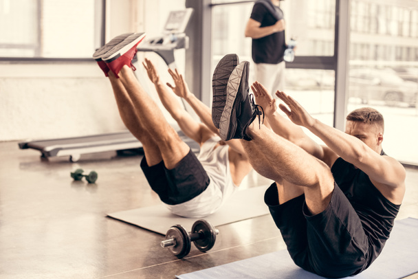 спортсмены одновременно тренируются на ковриках для йоги в тренажерном зале
 - Фото, изображение