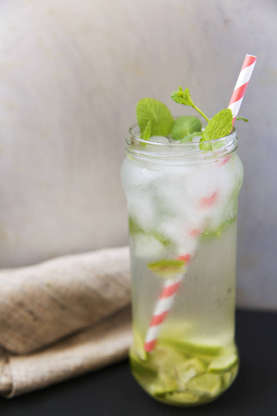 Summer drink with ice, fresh lime and mint on dark background. Side view. - Valokuva, kuva