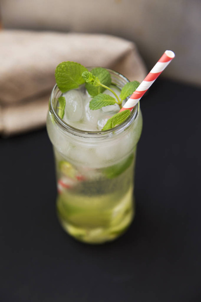 Summer drink with ice, fresh lime and mint on dark background. Side view. - Фото, зображення