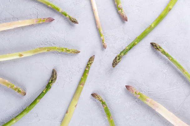 Food background. Raw asparagus flat lay pattern on a gray concrete background - Фото, зображення