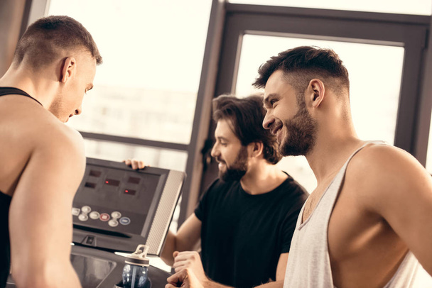 handsome sportsmen setting treadmill in gym - Photo, Image