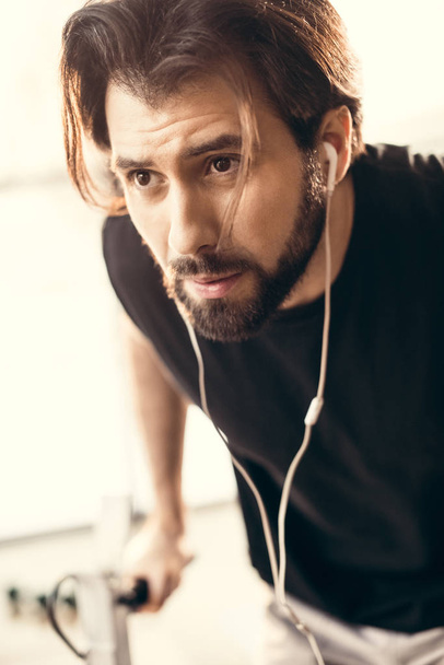 close-up view of bearded young sportsman training and looking away in gym - Fotó, kép