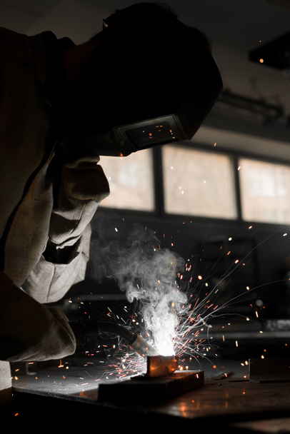 soldador en máscara de protección que trabaja con metal en fábrica
  - Foto, Imagen