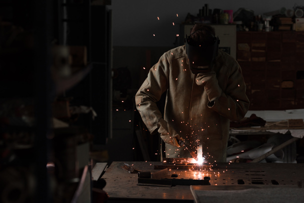 trabajador en la máscara de protección de soldadura de metal en fábrica
  - Foto, Imagen